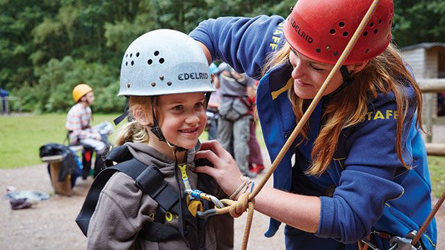 PGL Instructor adjusting a harness on a young Brownie